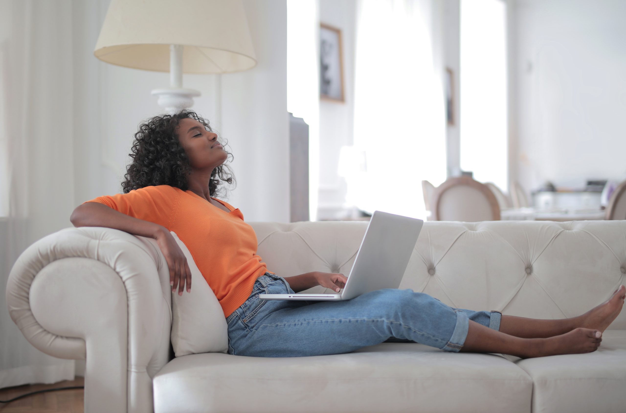 woman-in-orange-top-and-blue-denim-jeans-sitting-on-white-3961172